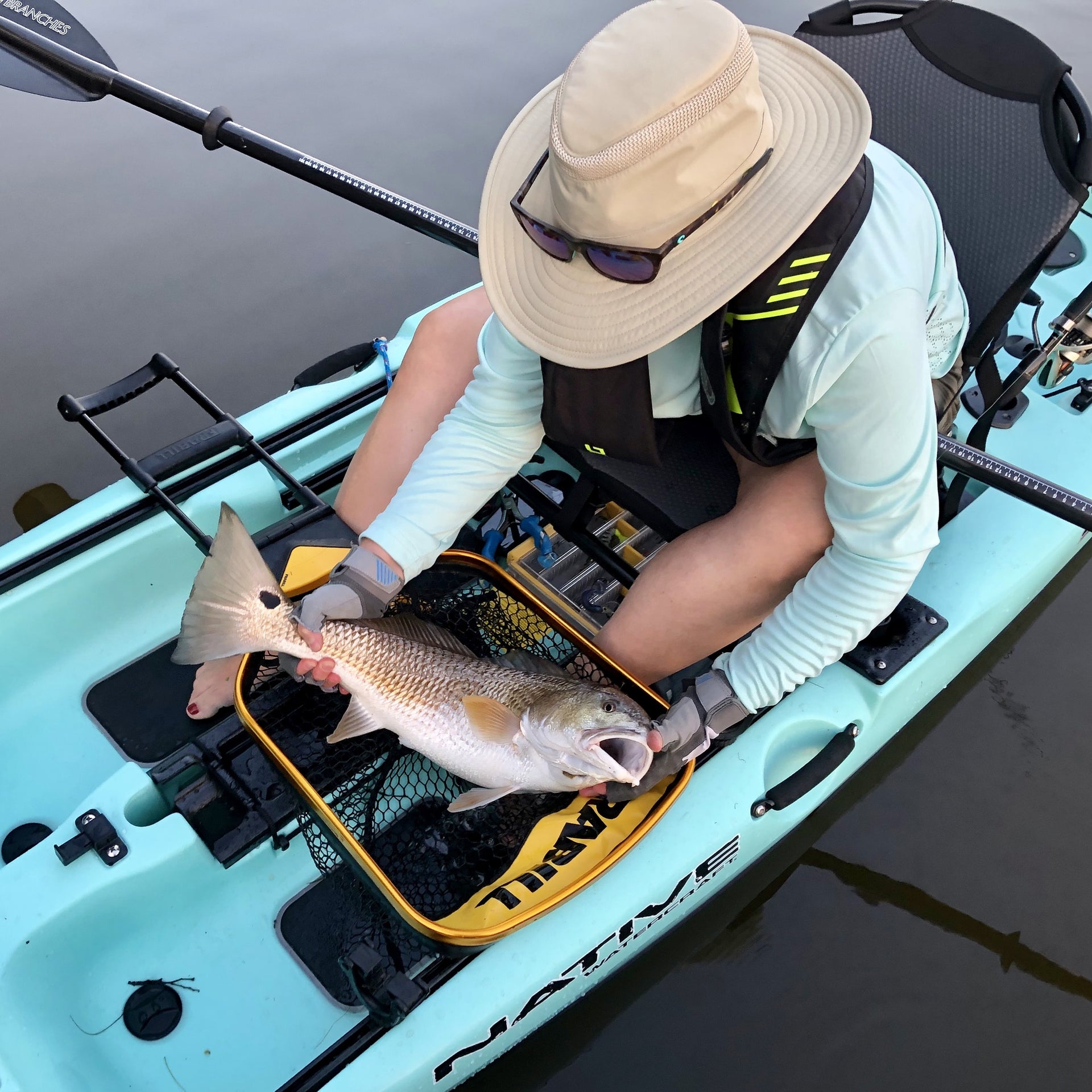 Guy on a kayak holding a fish over a net